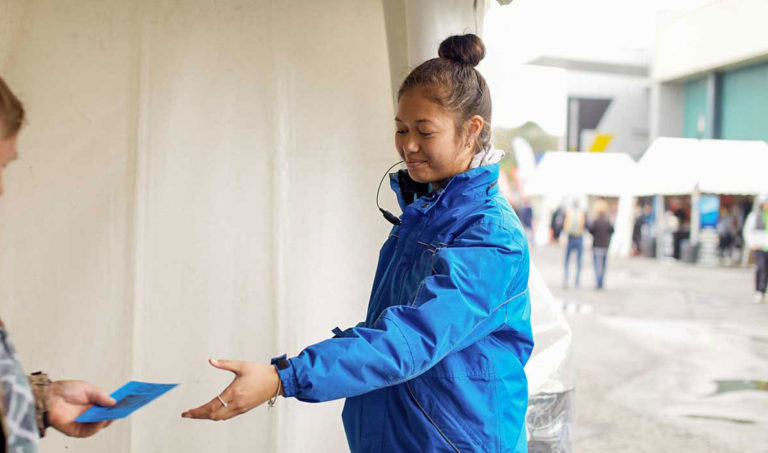 Security officer in a blue uniform directing people with a welcoming gesture.