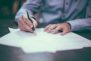 Person writing on documents at a desk, representing teaching, learning, and professional development.