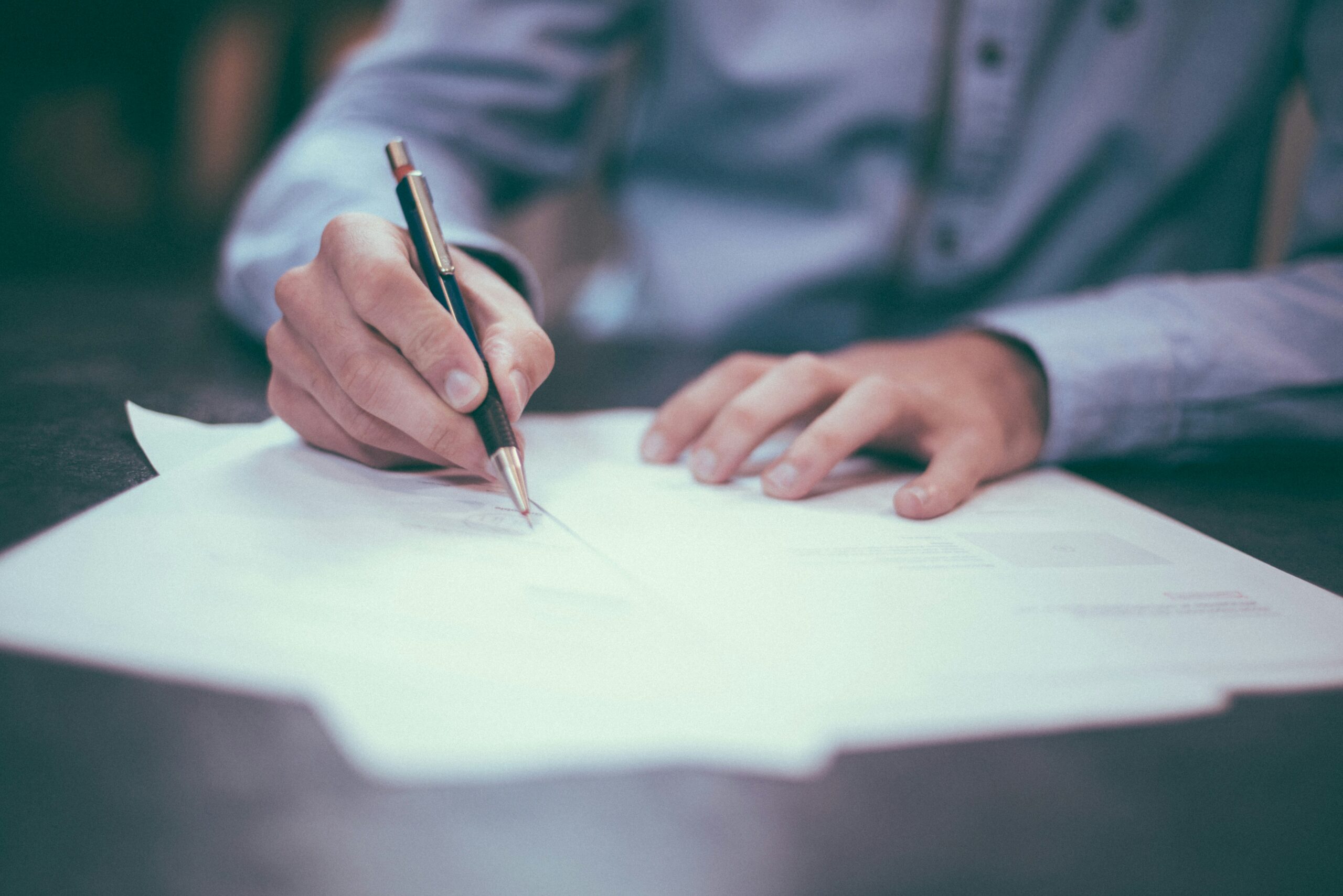 Person writing on documents at a desk, representing teaching, learning, and professional development.