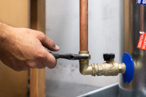 Close-up of an apprentice plumber tightening a fitting on copper piping.