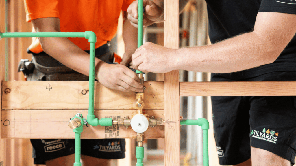 Apprentices installing plumbing pipes and fittings during on site training in New Zealand